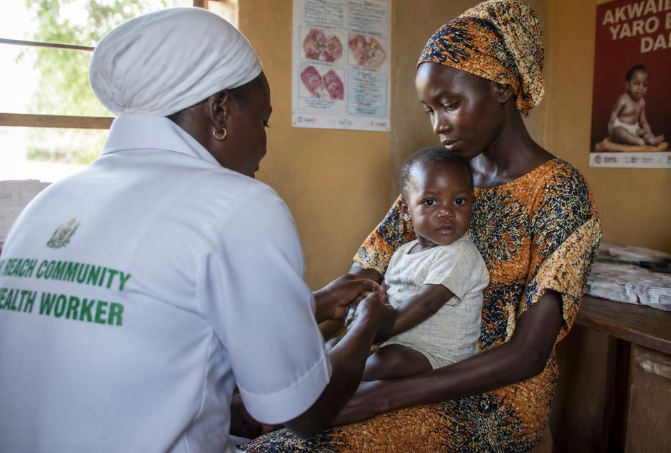 A community health worker caring for a mother and her baby at a rural clinic